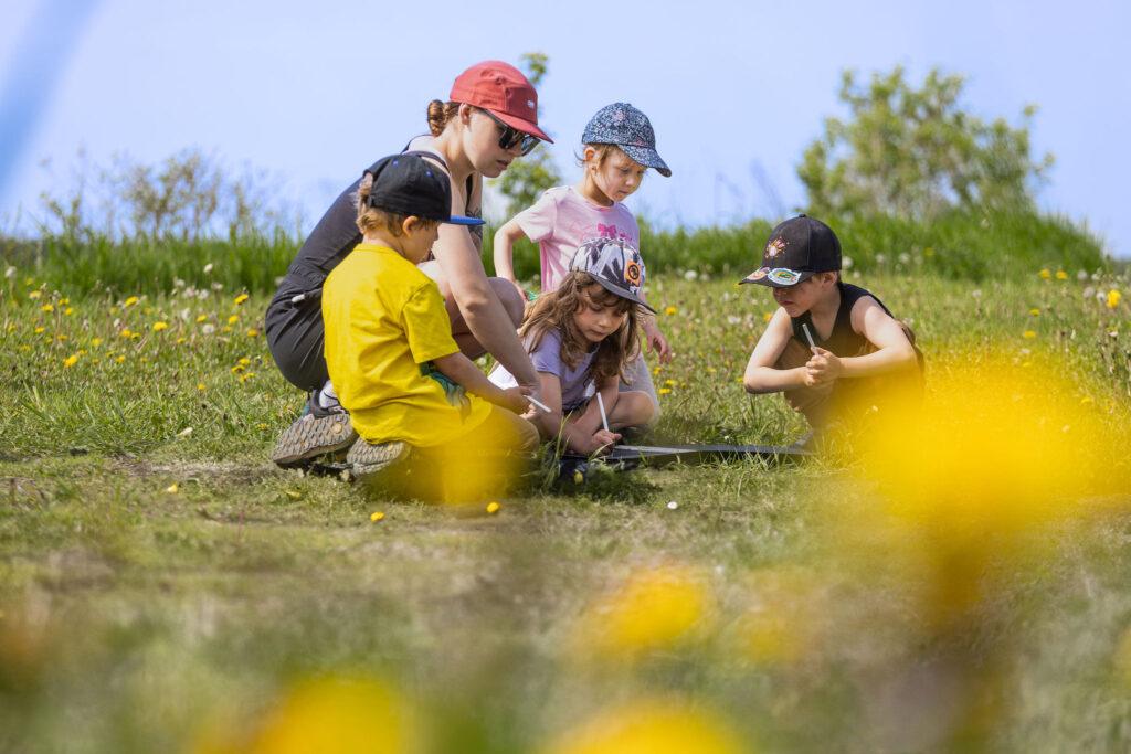 Photo d'un groupe d'enfants du CPE Flocon de rêve, à l'extérieur en été, supervisé par une éducatrice